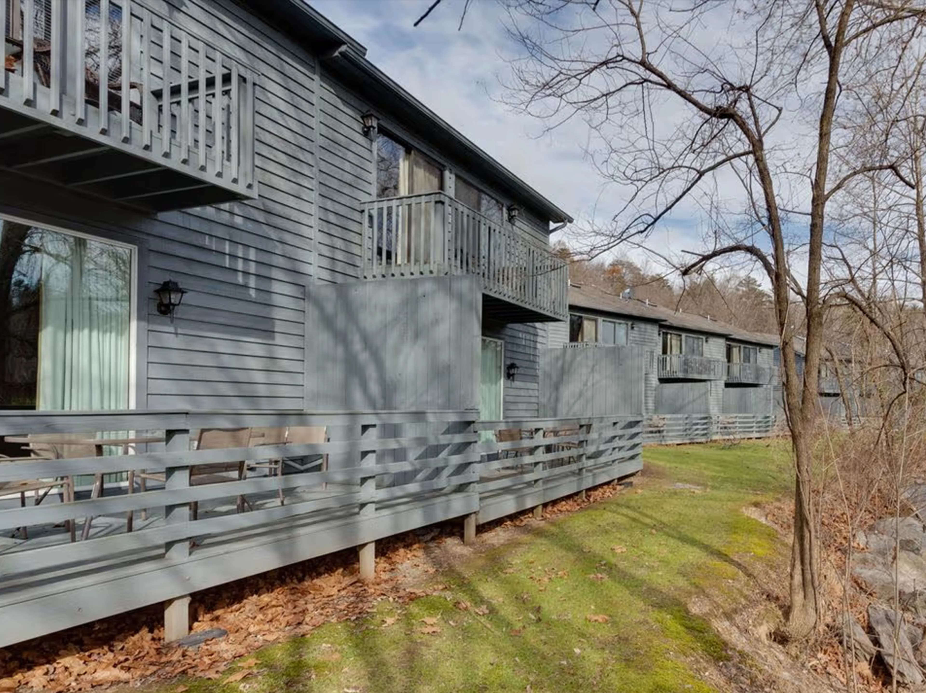 Row of modern cabins with spacious wooden decks overlooking a wooded area.